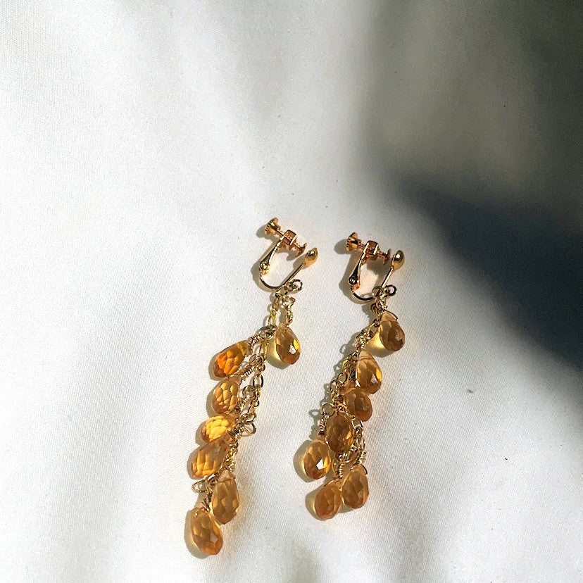 Screw back, clip-on earrings. Gold-plated brass throughout.  Seven faceted topaz briolettes dangling from 6" link chain.