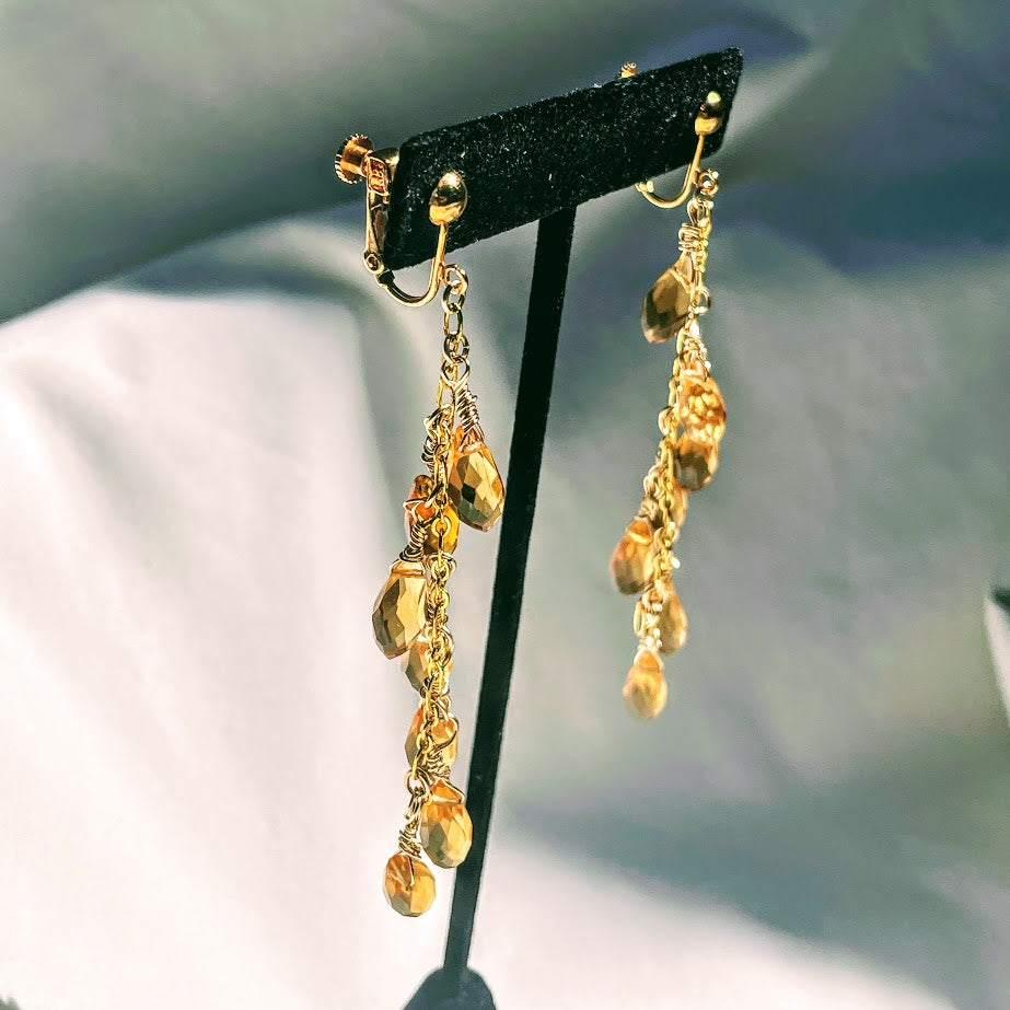 Screwback, clip-on earrings. Gold-plated brass throughout. Seven, faceted topaz glass briolettes dangling from 6" link chain.